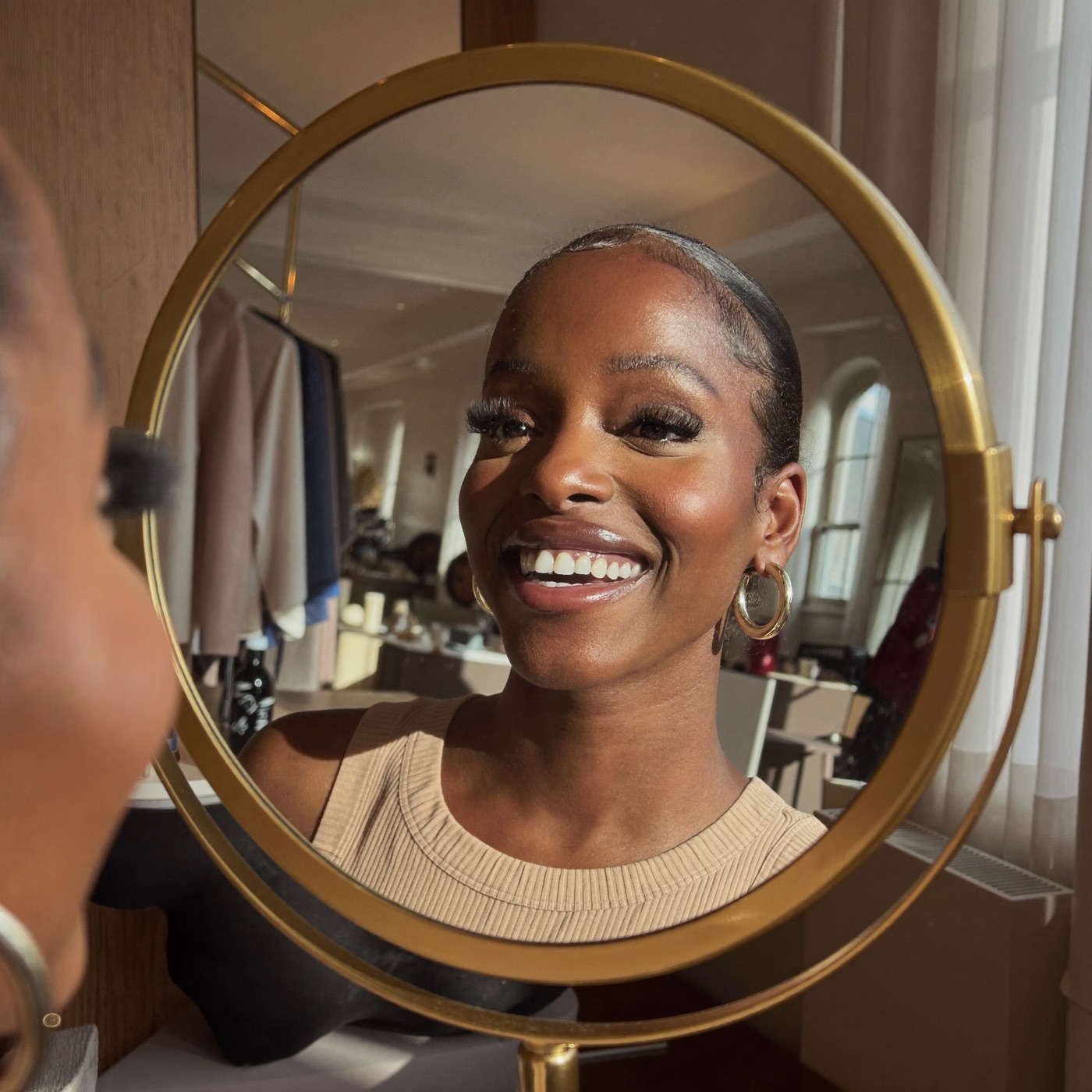 Smiling client admiring her new lash extensions in a gold mirror